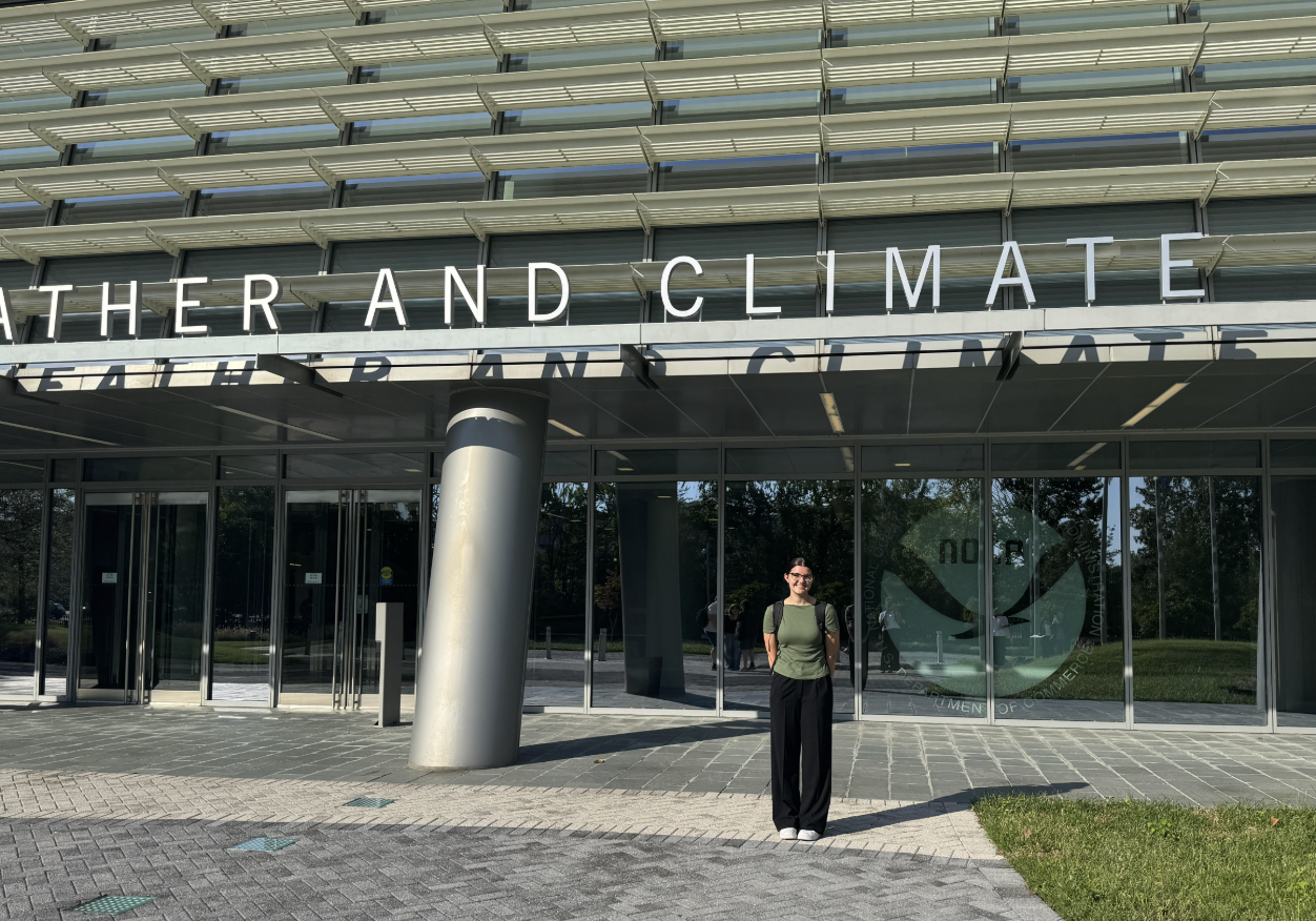 A young woman standing in front of the NOAA headquarters.